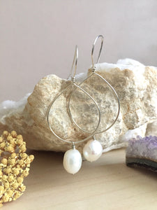 Sterling silver hoop earrings with a white freshwater pearl drop hanging from the hoop
