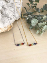 Load image into Gallery viewer, Rainbow bar necklaces laying on a table in a choice of silver or gold chain 