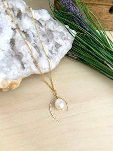 Wish bone shaped pendant necklace made from 14k gold fill wire and accompanied by a white freshwater pearl drop 
